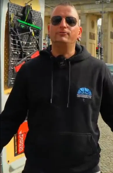 Benjamin O. Giese in Arbeitskleidung vor dem Einsatzfahrzeug mit Ausrüstungswand